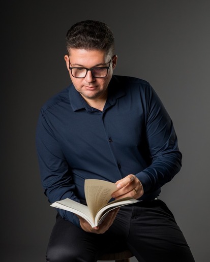 Dr. Samuel Ferro sentado em uma cadeira lendo um livro